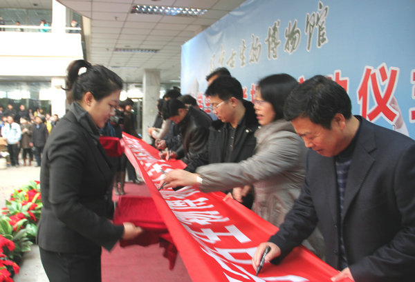 在印有"辽宁古生物博物馆大学生志愿者招募启动仪式"的条幅上签字留念